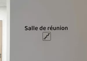 Photo d'un autocollant murale indiquant "Salle de réunion" avec une illustration représentant un escalier
