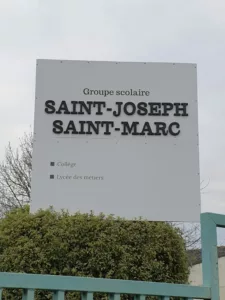 Photo d'un panneau marquant l'entrée d'un collège, on y lit "Groupe scolaire Saint-Joseph Saint-Marc"
