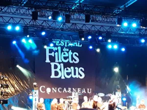 Photo d'une bannière géante type "fond de scène" pendant un concert en direct. Celle ci affiche : "Festival des Filets bleus, Concarneau"