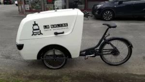 Vélo cargo équipé d'un caisson de transport avant marquée "La Balise, centre socioculturel"